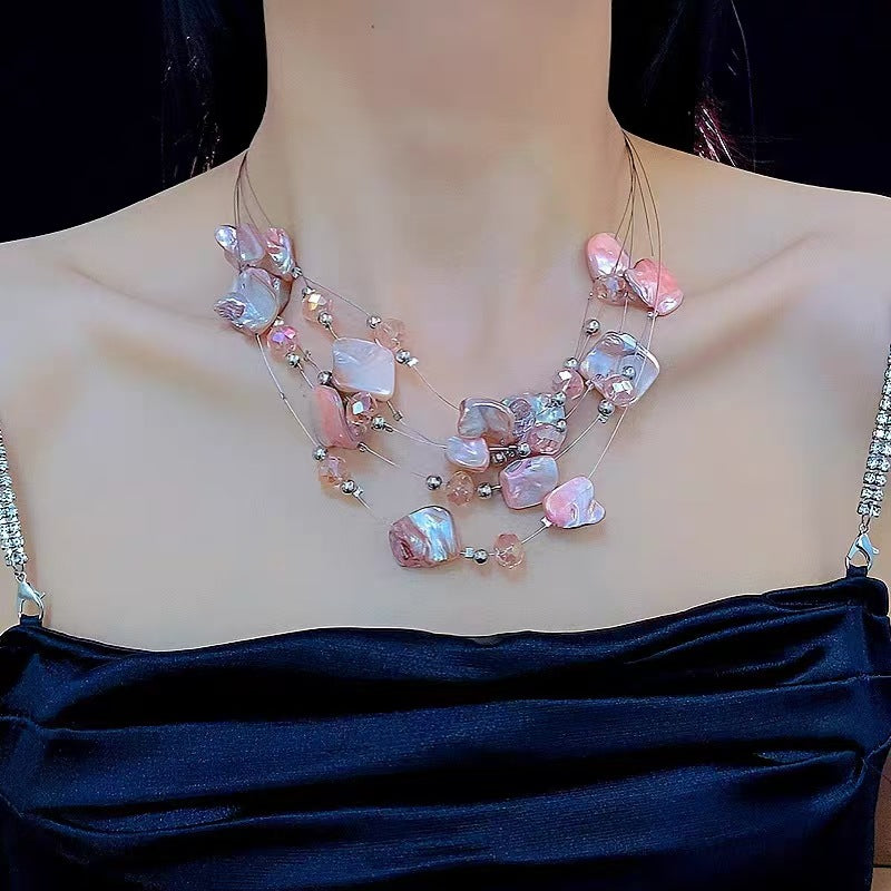 Woman wearing pink layered shell statement necklace with crystal details